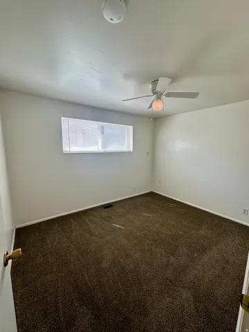 Carpeted room featuring a ceiling fan with integrated lighting, a window with horizontal blinds, and white baseboards