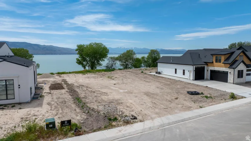 Expansive undeveloped lot with direct water frontage, offering a clear water backdrop and distant mountain peaks