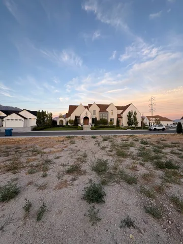 Stately residence featuring a stucco exterior with gabled rooflines, dark-framed windows, and an arched entry