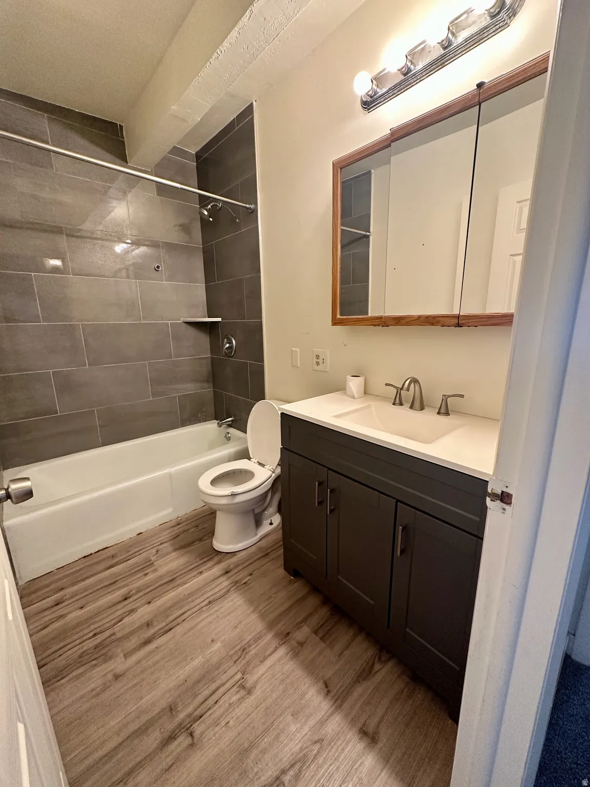 Bathroom featuring a dark gray vanity with a white countertop and undermount sink, framed mirror, and chrome vanity light fixture