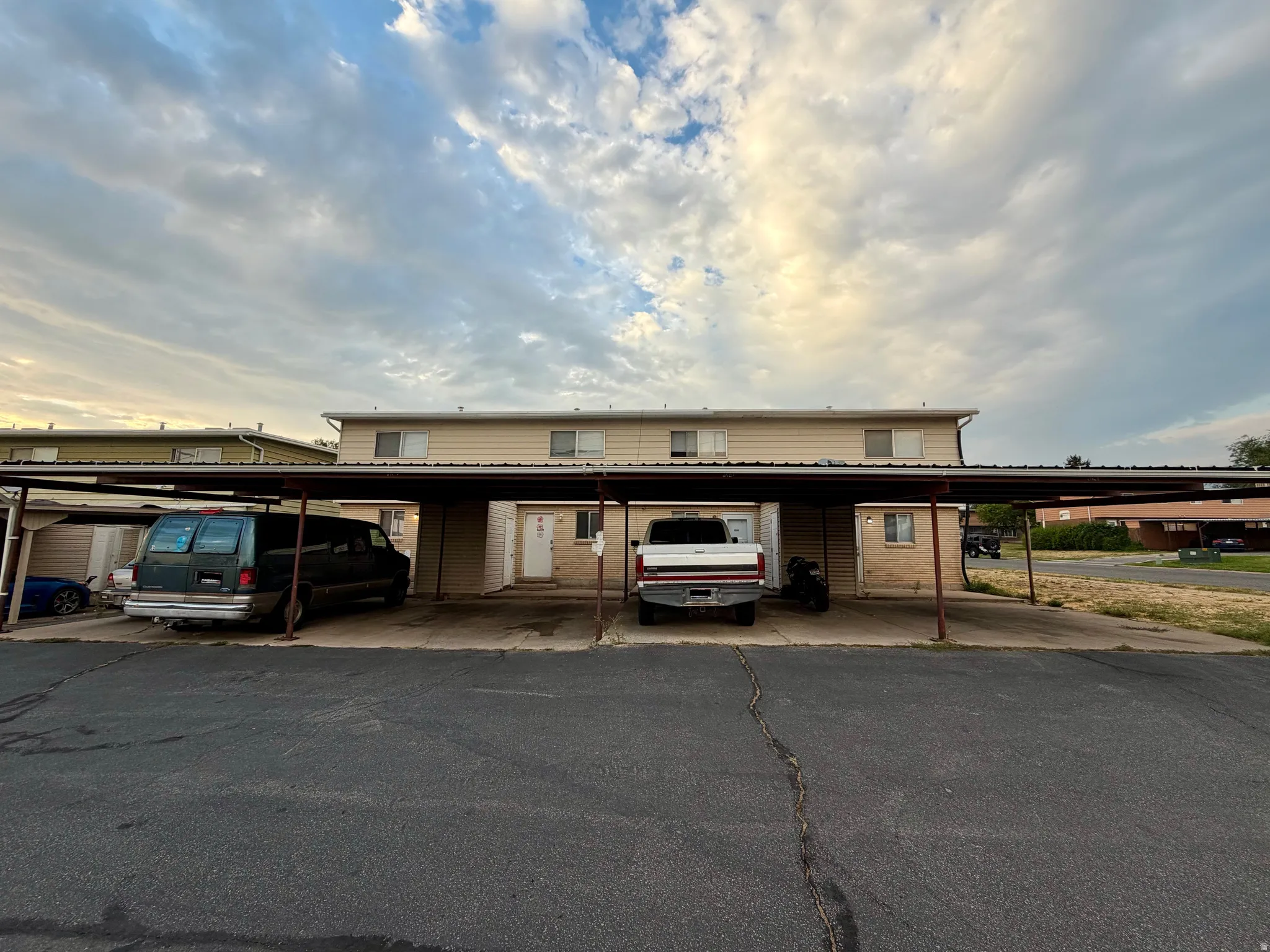 Multi-unit building featuring tan siding and a metal roof