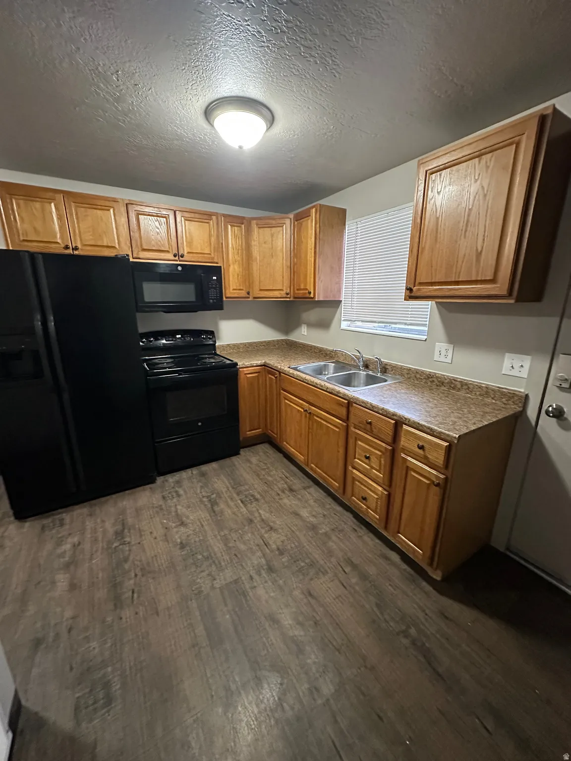 Kitchen featuring wood-finish flooring, wood cabinetry, laminate countertops, and stainless steel double sink