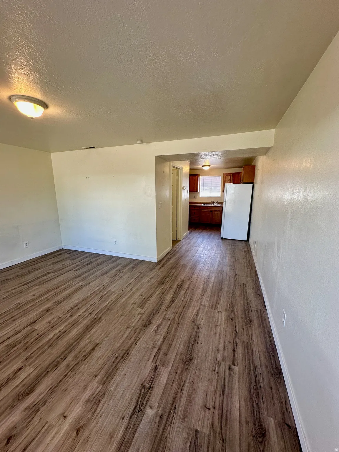Open-concept living space featuring wood-finish flooring, neutral wall tones, and recessed lighting