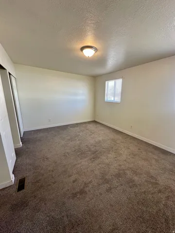 Carpeted room with a single window featuring horizontal blinds