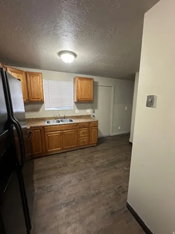 Kitchen featuring wood cabinetry, textured countertops, and a double basin sink