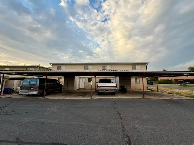 Multi-unit building featuring tan siding and a metal roof