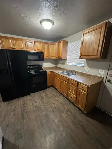 Kitchen featuring wood-finish flooring, wood cabinetry, laminate countertops, and stainless steel double sink