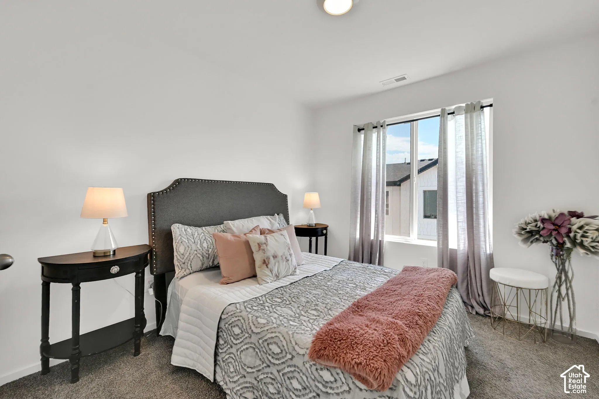 Carpeted bedroom featuring a window with vertical blinds, a bed with a fabric headboard, and recessed lighting