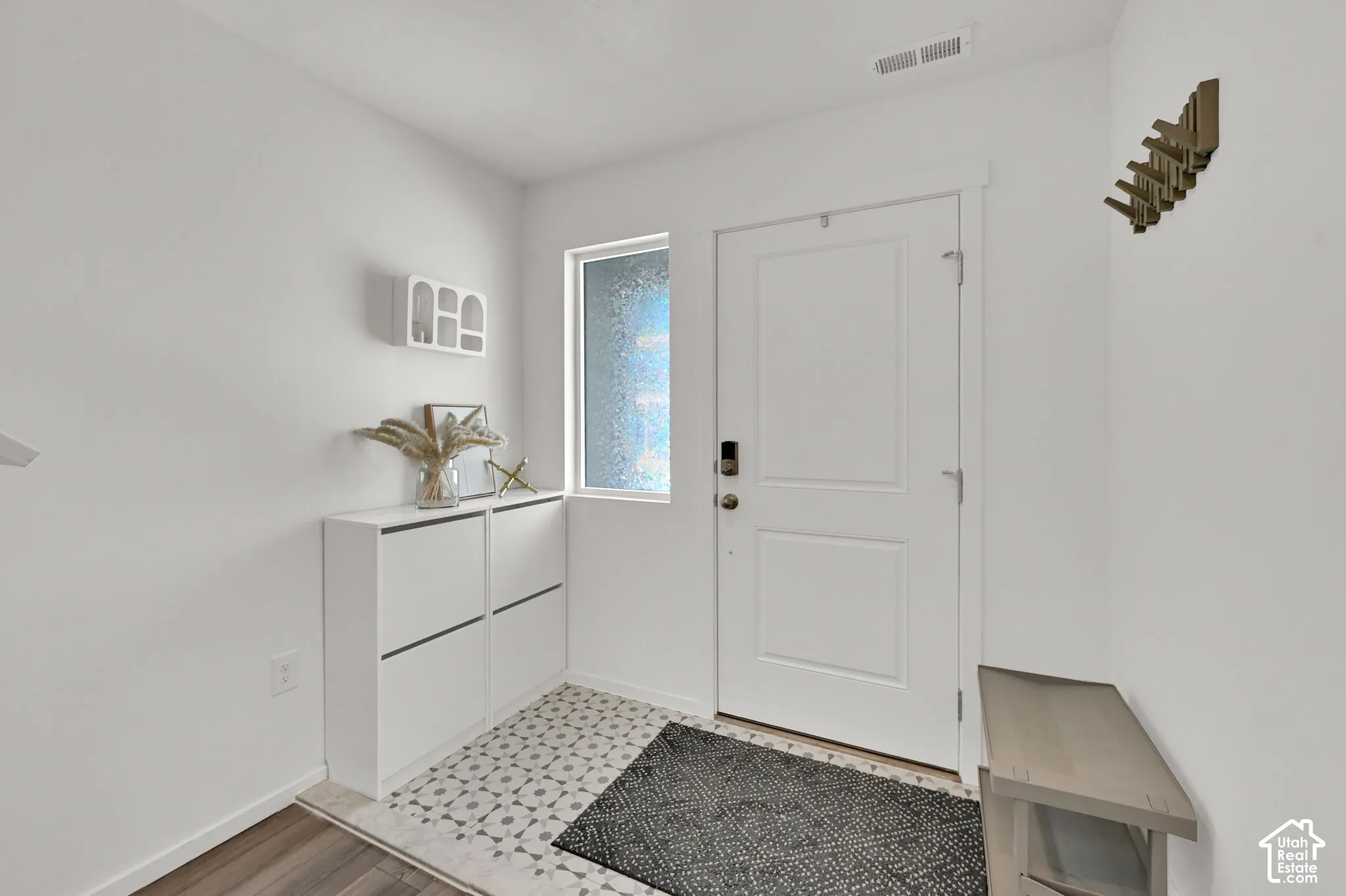 Entryway featuring a white paneled door with smart lock, an opaque side window, and an overhead ventilation register