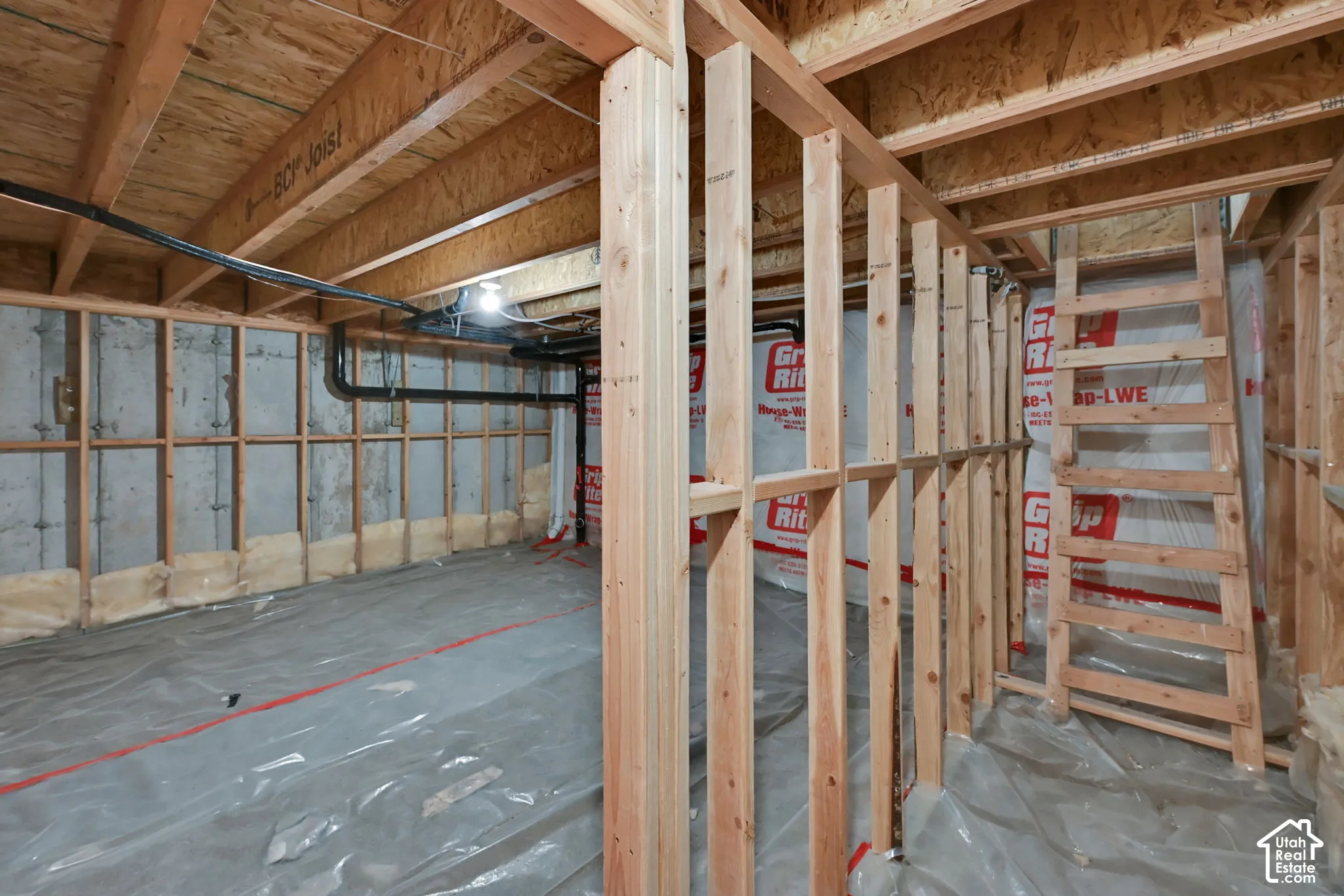 Unfinished basement space featuring exposed wood framing, concrete foundation walls, plumbing lines, and subfloor ceiling
