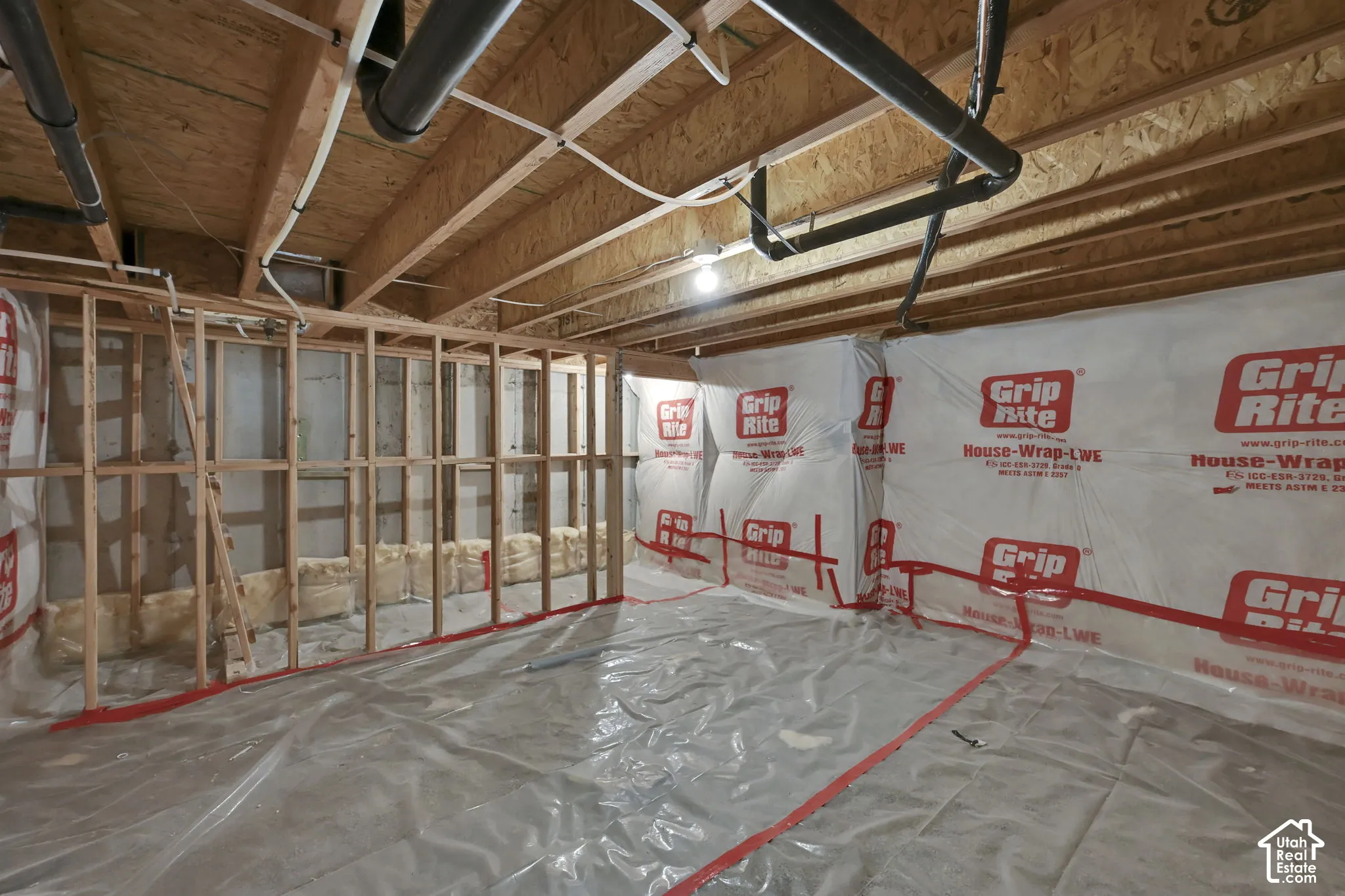 Unfinished basement space featuring visible wood framing, exposed ceiling joists, and visible plumbing