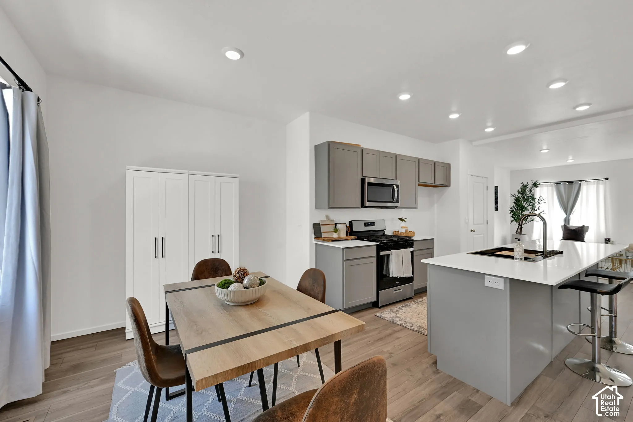 Open-concept kitchen and dining area featuring light wood-finish flooring, recessed lighting, and a white color palette