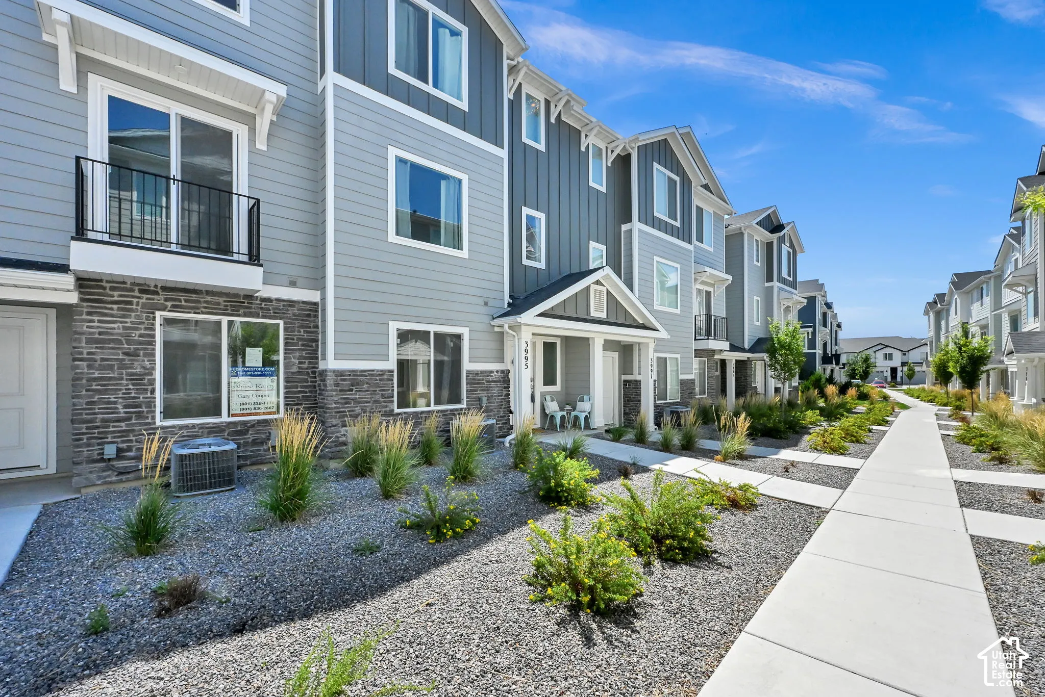 Modern townhome exterior featuring multi-toned siding, stacked stone accents, and a covered entry
