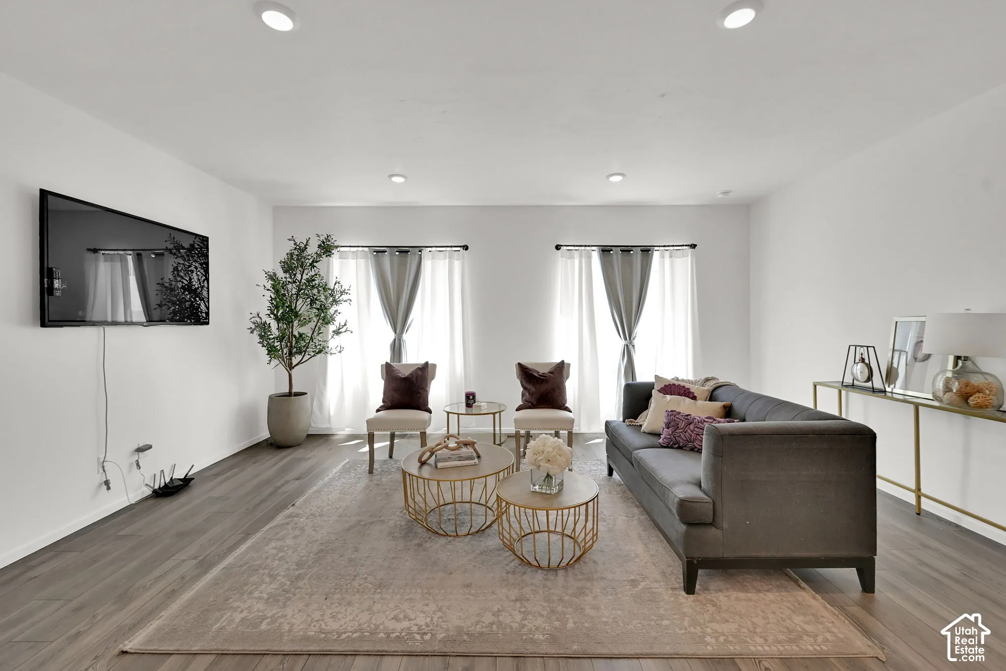 Living area featuring wood-finish flooring, recessed lighting, and dual windows with curtain rods