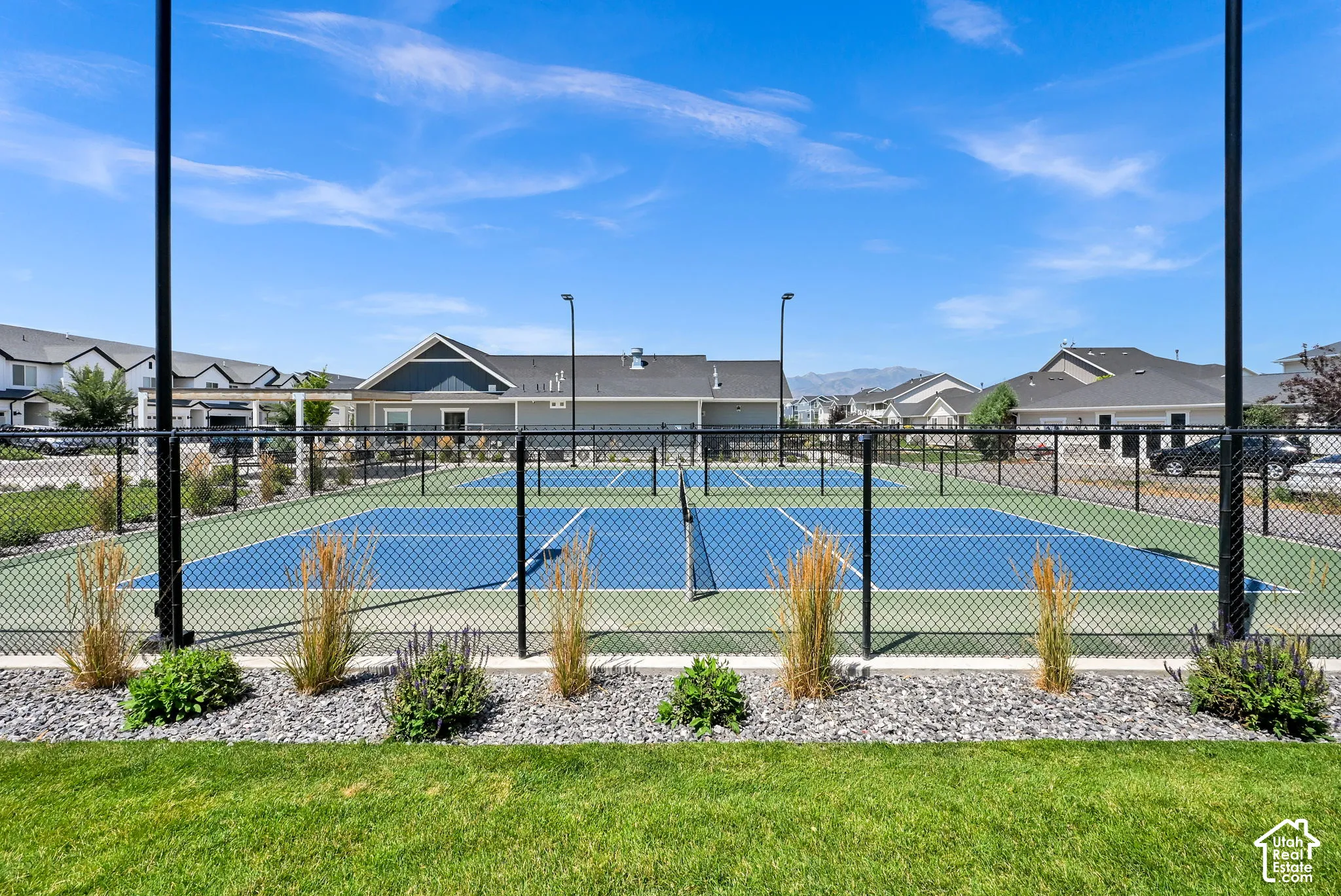 Fenced multi-sport court featuring two blue and green playing surfaces, multiple nets, and perimeter lighting