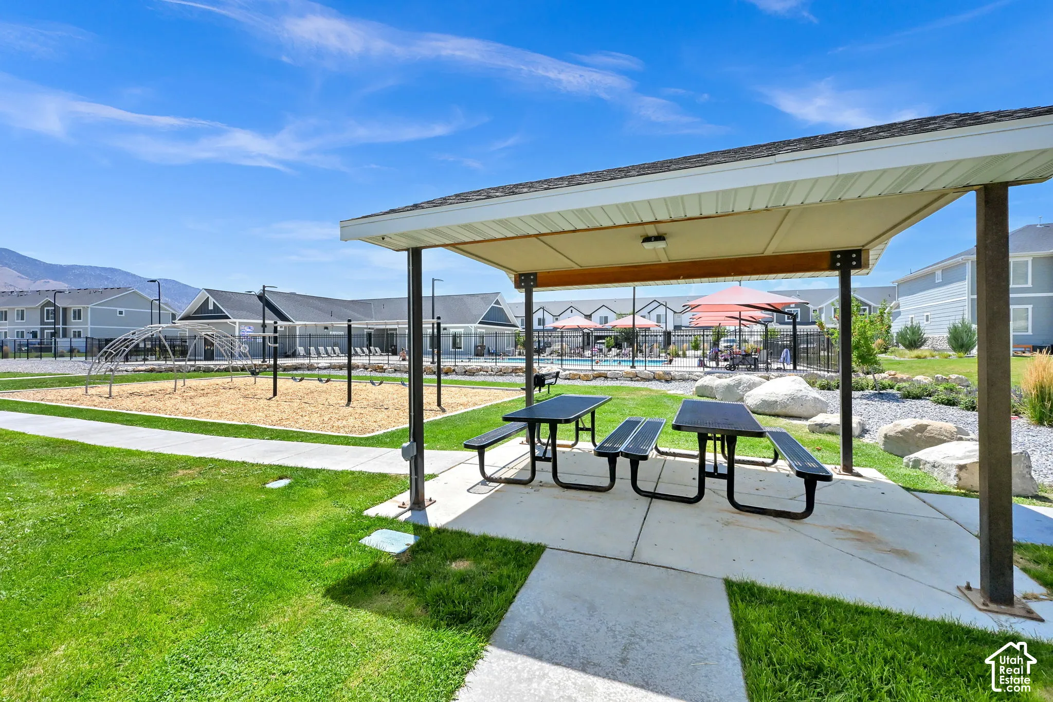 Covered patio space featuring two picnic tables, concrete flooring, and a flat roof