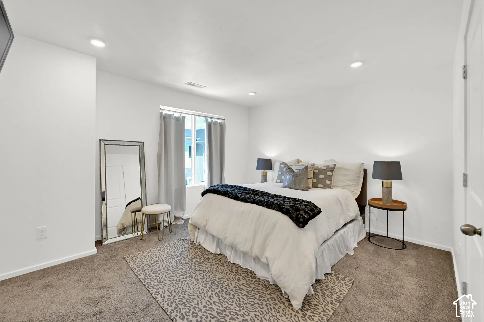 Bright bedroom featuring recessed lighting, a window with drapery, and neutral carpeting