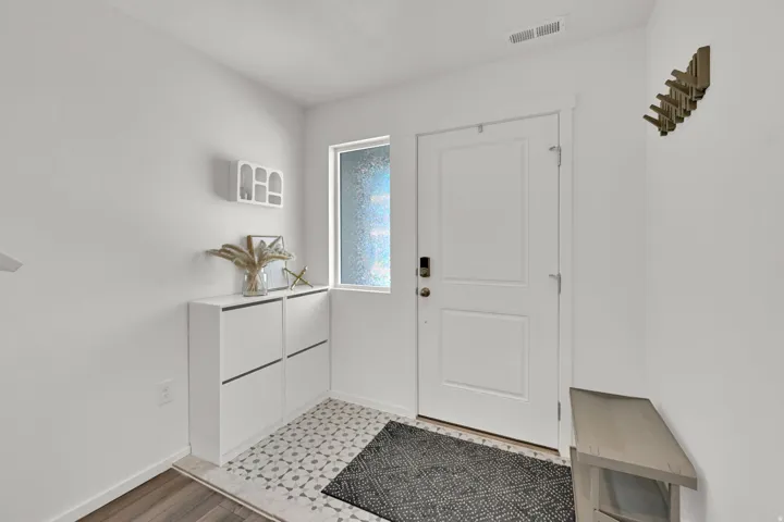 Entryway featuring a white paneled door with smart lock, an opaque side window, and an overhead ventilation register