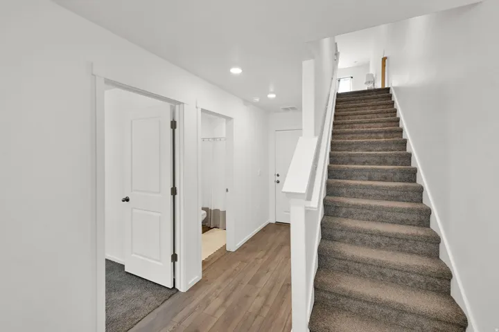 Staircase featuring carpeted treads and a painted white handrail