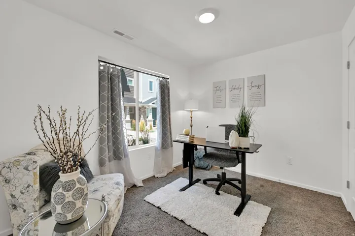 Bright interior room featuring a large window, recessed ceiling light, white walls, and carpeting