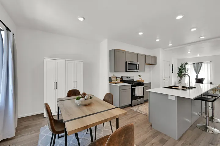 Open-concept kitchen and dining area featuring light wood-finish flooring, recessed lighting, and a white color palette