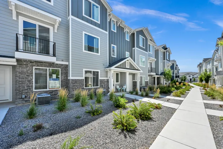 Modern townhome exterior featuring multi-toned siding, stacked stone accents, and a covered entry