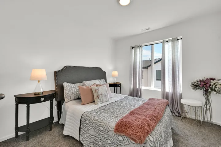 Carpeted bedroom featuring a window with vertical blinds, a bed with a fabric headboard, and recessed lighting