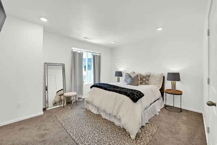 Bright bedroom featuring recessed lighting, a window with drapery, and neutral carpeting