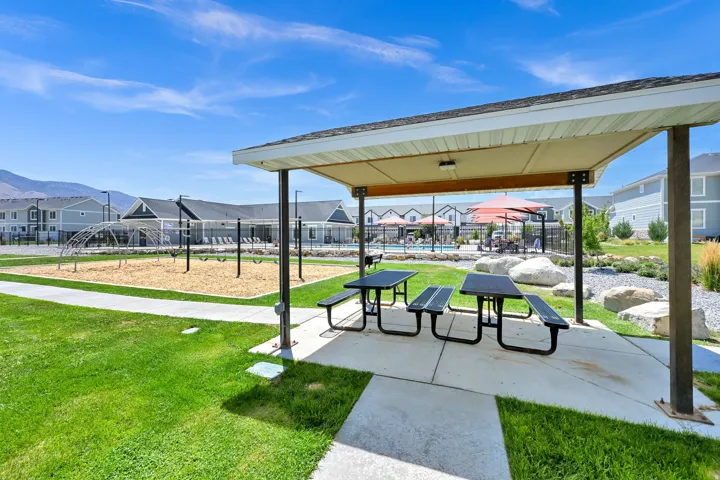 Covered patio space featuring two picnic tables, concrete flooring, and a flat roof