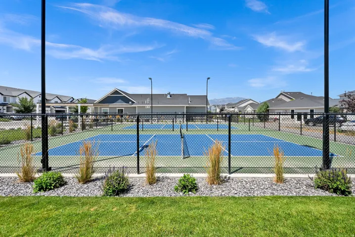 Fenced multi-sport court featuring two blue and green playing surfaces, multiple nets, and perimeter lighting