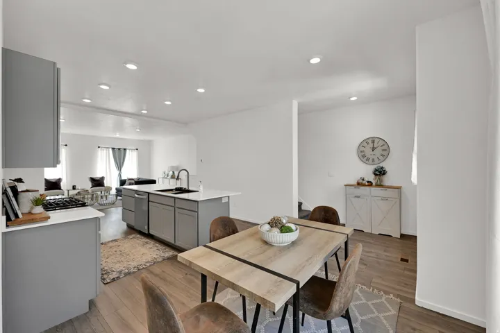 Open-concept kitchen and dining area featuring light wood-finish flooring, recessed lighting, and a modern kitchen island with a built-in sink