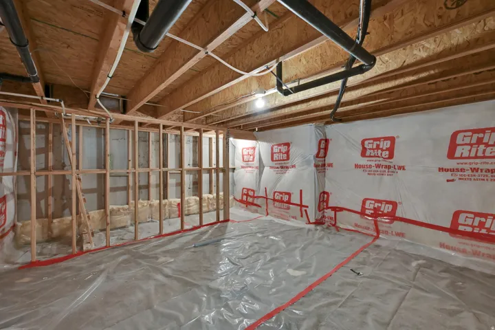 Unfinished basement space featuring visible wood framing, exposed ceiling joists, and visible plumbing
