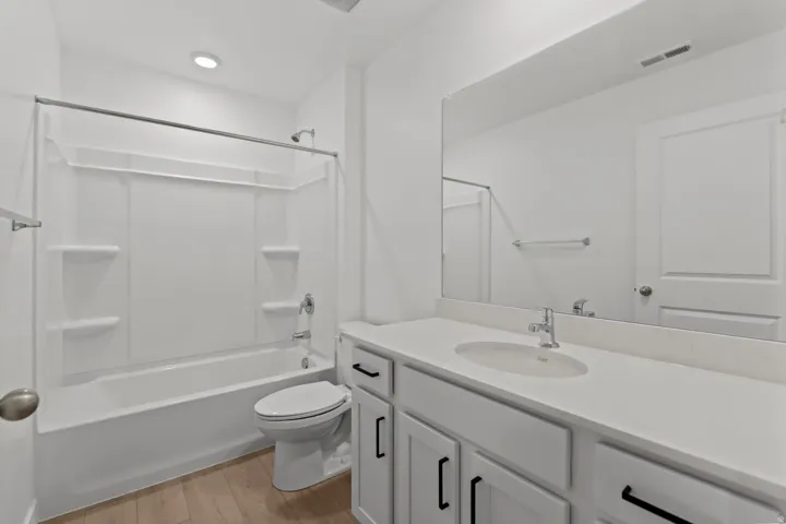 Bathroom featuring a single vanity with an integrated sink, a white countertop, and a large mirror