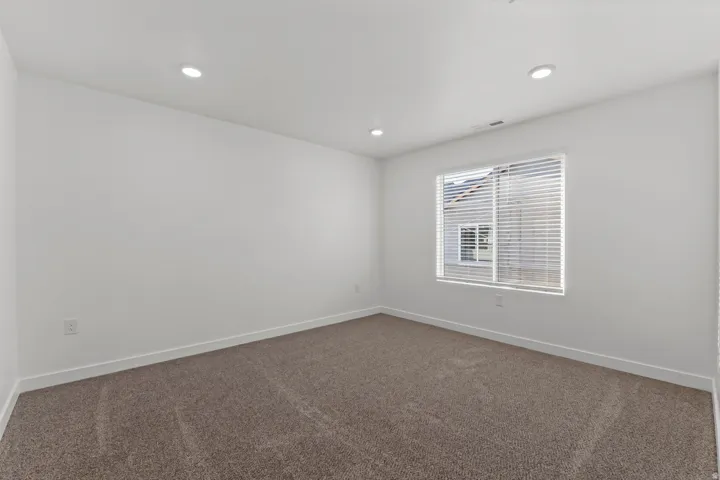 Carpeted room with recessed lighting and a window featuring horizontal blinds