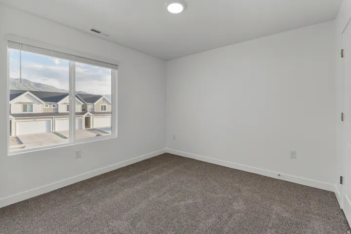 Bright room featuring neutral-toned carpet, white walls, and a large window