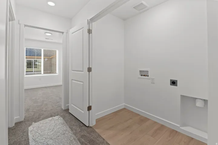 Dedicated utility space featuring light wood-finish flooring, recessed lighting, and white baseboards