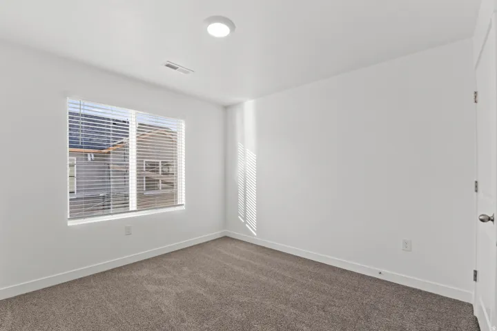 Bright interior space featuring a double window with horizontal blinds, neutral wall paint, recessed lighting, and soft carpet flooring