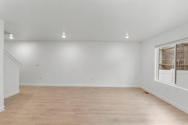 Spacious room featuring light wood-finish flooring, recessed lighting, and a large window with white trim