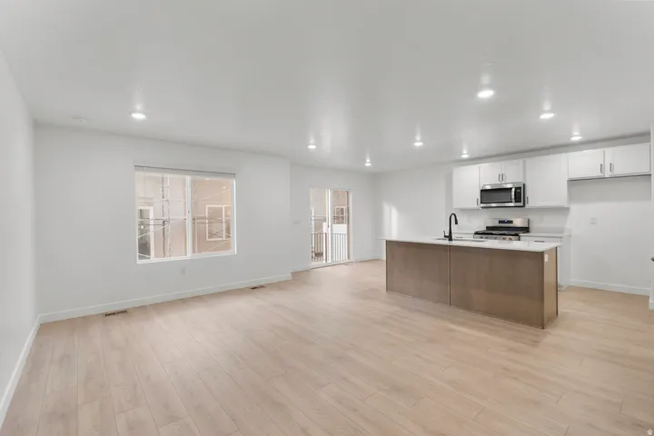 Open-concept living space featuring wood-finish flooring, recessed lighting, and a window for natural illumination