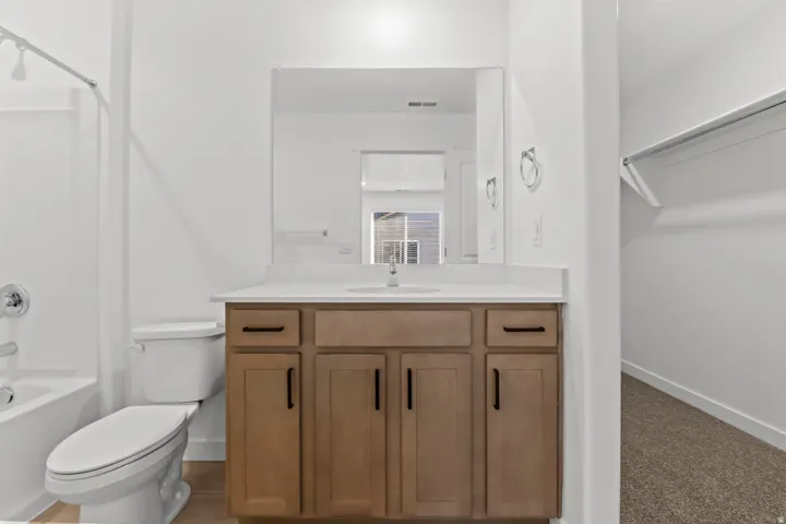 Bathroom featuring a single vanity with wood-finish cabinetry, a white countertop, and a rectangular mirror