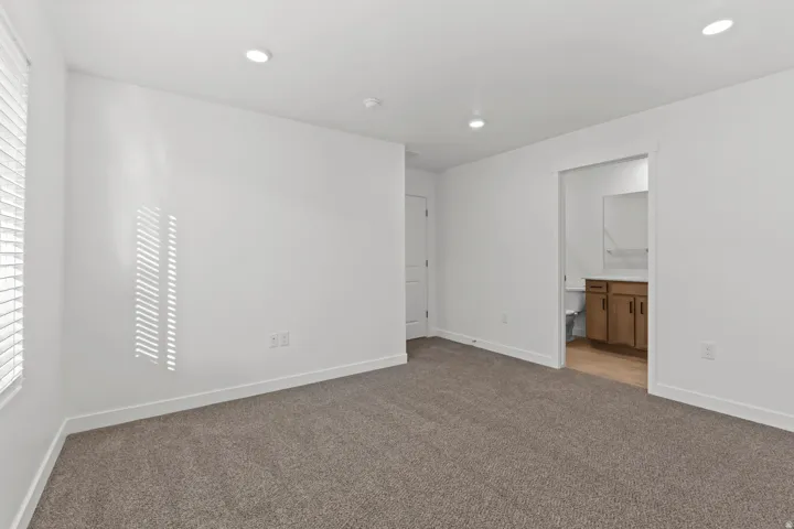 Spacious room featuring neutral carpet flooring, recessed lighting, and a window with blinds