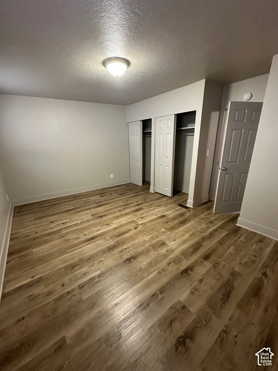 Spacious room featuring wood-finish flooring, light gray walls, and white baseboards