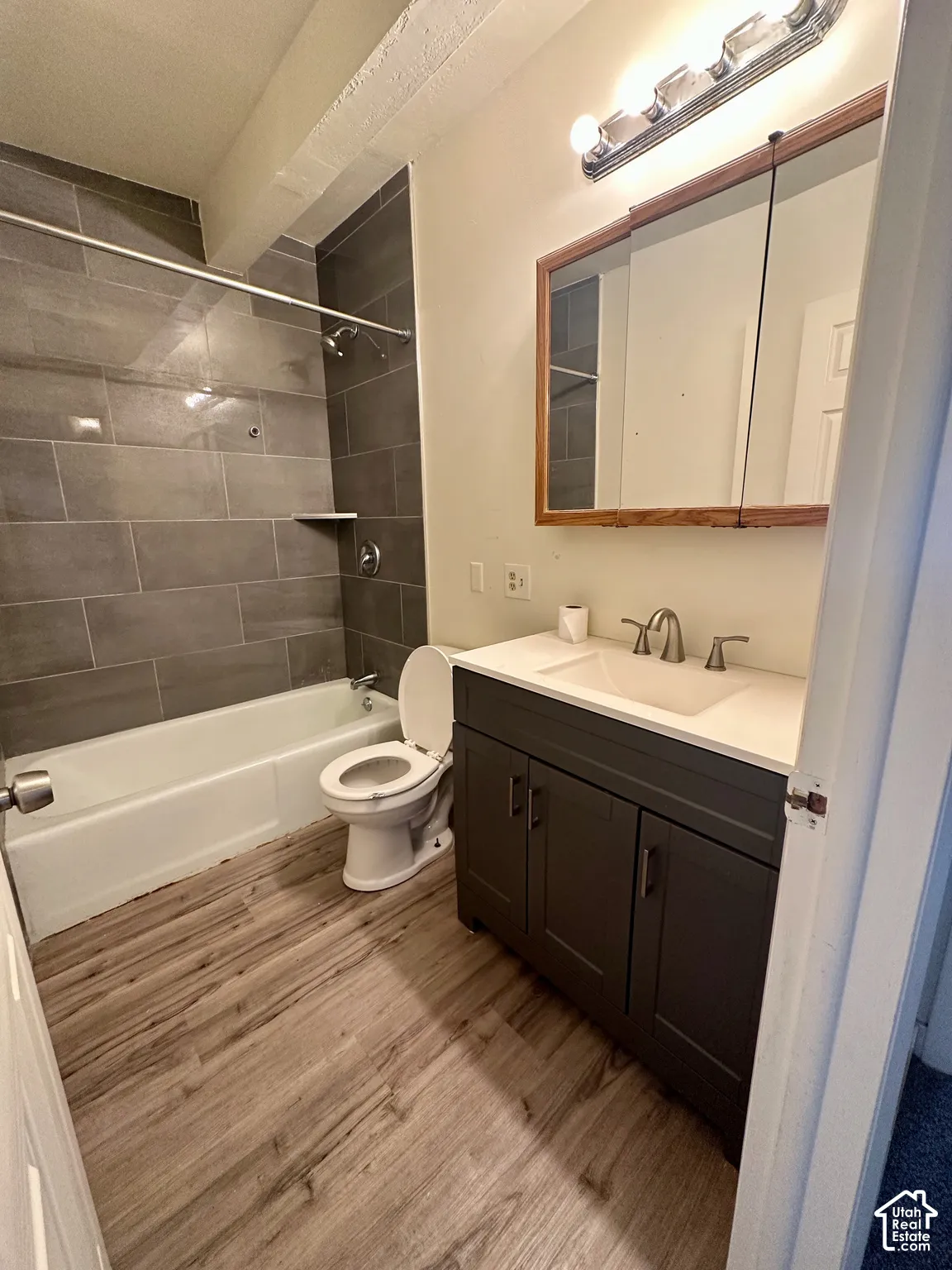 Bathroom featuring a dark gray vanity with a white countertop and undermount sink, framed mirror, and chrome vanity light fixture