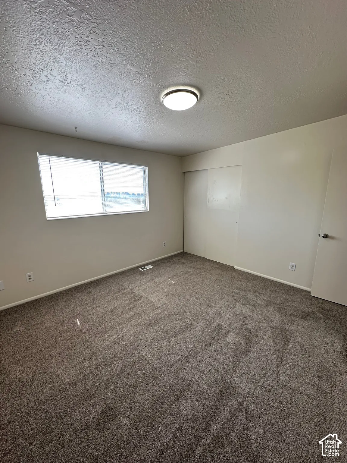 Neutral-toned wall paint complements the textured ceiling and dark gray carpeting