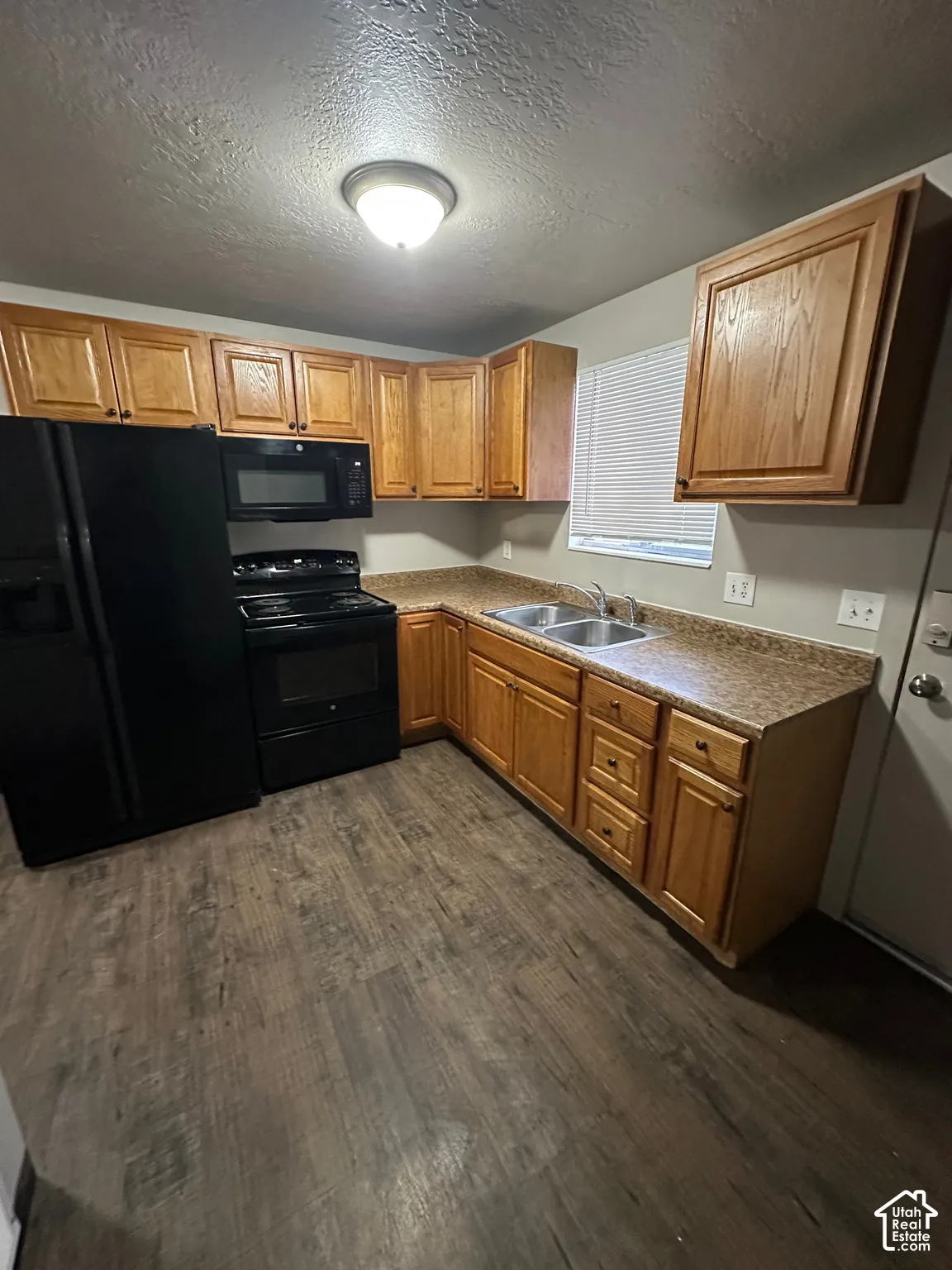 Kitchen featuring wood-finish flooring, wood cabinetry, laminate countertops, and stainless steel double sink