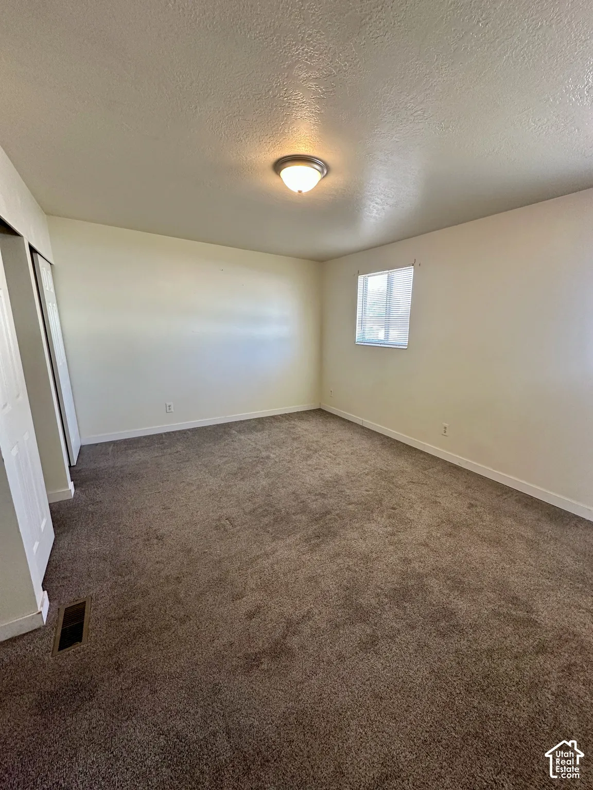 Carpeted room with a single window featuring horizontal blinds