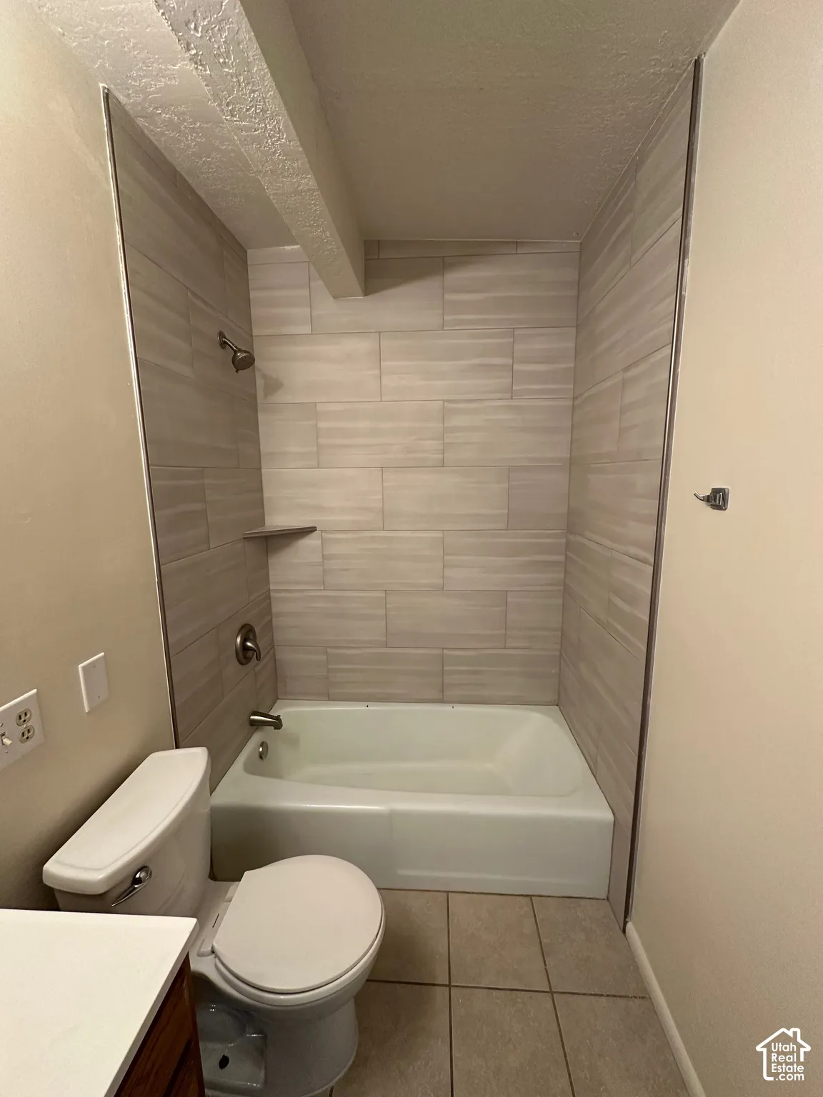 Bathroom featuring a tiled shower surround with a built-in shelf, bathtub, and toilet