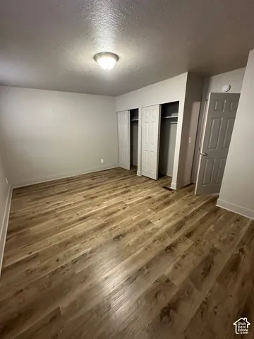 Spacious room featuring wood-finish flooring, light gray walls, and white baseboards