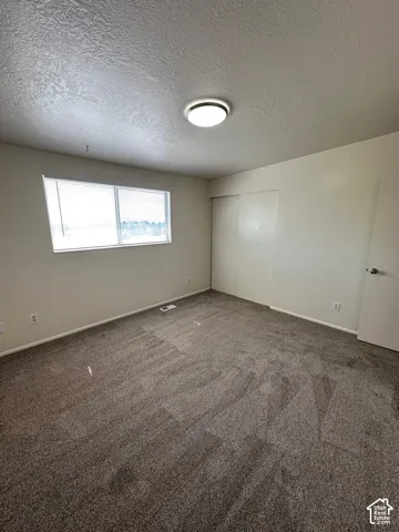 Neutral-toned wall paint complements the textured ceiling and dark gray carpeting