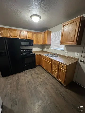 Kitchen featuring wood-finish flooring, wood cabinetry, laminate countertops, and stainless steel double sink